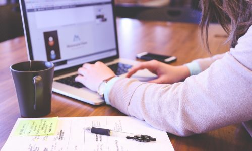 Close-up of Woman's hands working on a laptop with notes and paper next to her. Preparing Students for the Rigors of College